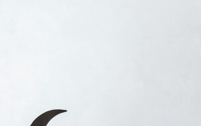 tulisan "Ramadan Mubarak" yang dihias dengan hiasan bulan sabit dan gantungan berwarna kuning. Tulisan dan hiasan ini diletakkan di atas latar belakang berwarna putih.