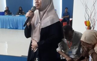 MC disabilitas netra berdiri di atas panggung dengan mikrofon di tangannya-fungsi teman tandem
