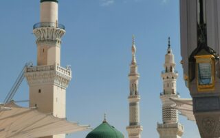 Masjid Nabawi dengan kubah hijau dan menara tinggi berlatar langit biru dan awan putih