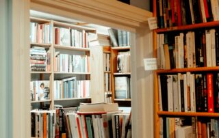 Ruang dipenuhi rak dengan buku yang tersusun sesuai warna. Di atas pintu terdapat tulisan Biography tips MC