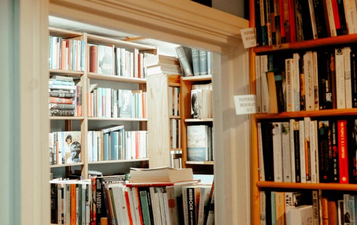 Ruang dipenuhi rak dengan buku yang tersusun sesuai warna. Di atas pintu terdapat tulisan Biography tips MC