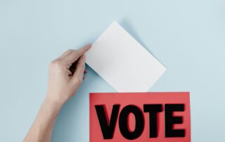 tangan memasukkan surat suara ke dalam kotak suara Pilkada 2024